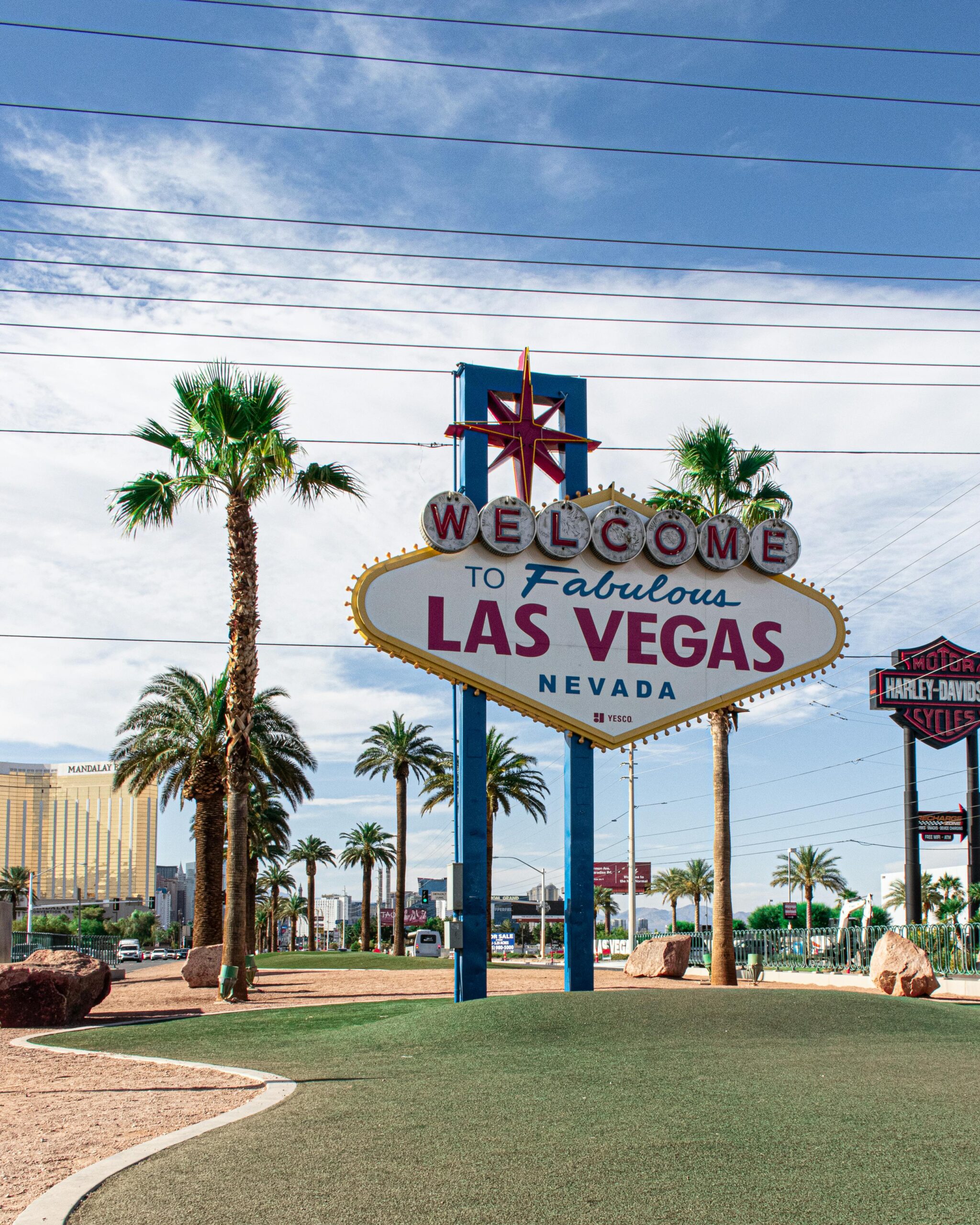 Famous Welcome to Las Vegas sign surrounded by palm trees on a sunny day.