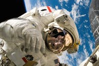 Astronaut floating in space during a spacewalk, visible Earth in the background.